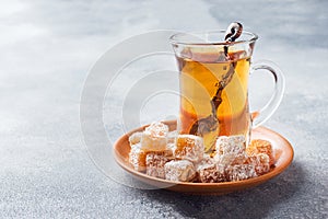 Turkish delight with hazelnut in carved metal bowl and tea in glass Cup, selective focus