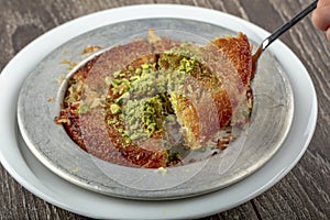 Turkish dessert kunefe, kunafa, kadayif with pistachio powder and cheese hot eaten a sweet