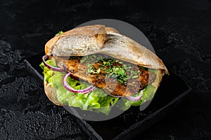 Turkish fish sandwich with grilled mackerel fillet Balik Ekmek. Black background. Top view