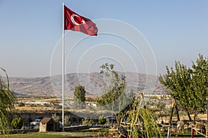 Turkish flag near the horizon in GÃ¶reme, Cappadoci. Tourist town with houses in Cappadocia