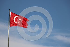 Turkish flag, flag pole, blue sky.