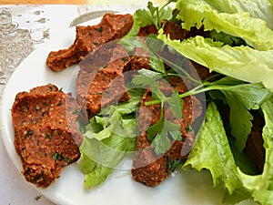 Turkish Food Cig Kofte with lettuce and parsley in plate.