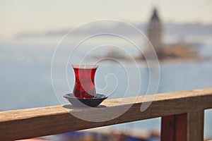 Turkish glass in form of a tulip filled with hot black tea with view to Maiden\'s Tower in Uskudar, Istanbul