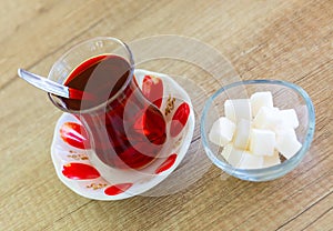 Turkish hot black tea served in traditional glass with sugar cubes