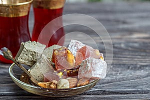 Turkish joys with different nuts are a glass of tea and a spoon. Eastern sweets. Traditional Turkish delight Rahat lokum on a