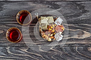 Turkish joys with different nuts is a glass of tea and a spoon. Eastern sweets. Traditional Turkish delight Rahat lokum on a