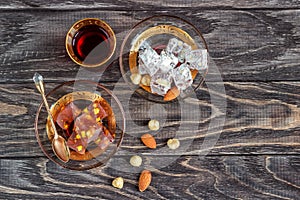 Turkish joys with different nuts is a glass of tea and a spoon. Eastern sweets. Traditional Turkish delight Rahat lokum on a