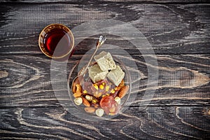 Turkish joys with different nuts is a glass of tea and a spoon. Eastern sweets. Traditional Turkish delight Rahat lokum on a