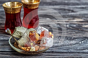 Turkish joys with different nuts are a glass of tea and a spoon. Eastern sweets. Traditional Turkish delight Rahat lokum on a