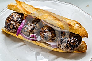 Turkish Kofte Ekmek / Meatball Sandwich with Red Onions. Traditional Fast Food from Turkey