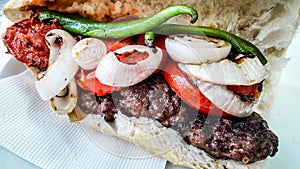 Turkish Kofte Ekmek / Meatball Sandwich with tomatoes, onion and green pepper.