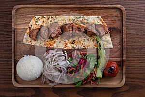 Turkish lamb sis kebab with rice and vegetables on wooden table