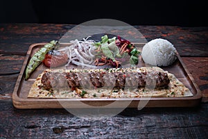 Turkish lula lamb or beef kebab with rice and vegetables on rustic wooden table