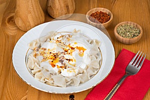 Turkish Manti (ravioli) on plate with red pepper, butter, sauce, yogurt and mint