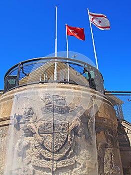Turkish and north cyprus flags flying above and old building with the remains of a british coat of arms in nicosia