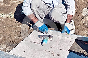 Pavement construction worker using a water level tool for balancing the tiles