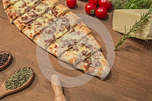 Turkish pide with cubed meat and cheese on wooden background