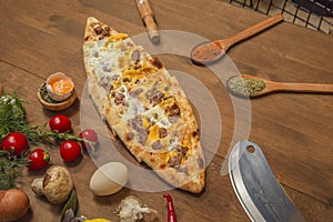 Turkish pide with cubed meat and cheese on wooden background