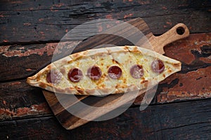 Turkish pide with sausage on rustic wooden table photo