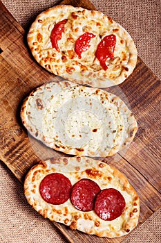 Turkish pita bread on a wooden cutting board. Mini pizzas