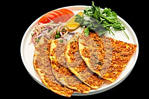 Turkish pizza lahmajun on a white plate with a slice of lemon, tomatoes decorated with a branch of parsley