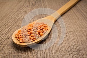 Turkish Red Lentil legume. Spoon and grains over wooden table.