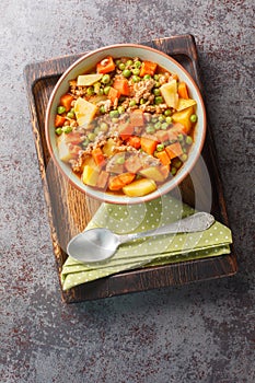 Turkish stew Kiymali bezelye yemegi with green peas, minced meat and vegetables closeup on the plate. Vertical top view