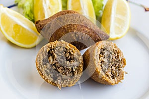 Turkish Stuffed Meatballs icli kofte with sliced lemons and lettuce.