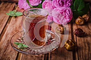 Turkish tea in a glass cup and dried dates fruits on wooden background. Ramadan food. Selective focus
