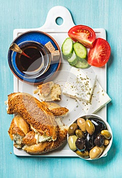 Turkish traditional breakfast with feta cheese, vegetables, olives, simit bagel and tea