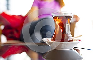 Turkish woman drinking traditional Turkish tea from ince belli bardak photo