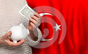 Turkish woman with money bank on the background of Turkey flag. Dotations, pension fund, poverty, wealth, retirement concept