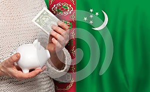 Turkmen woman with money bank on the background of Turkmenistan flag. Dotations, pension fund, poverty, wealth, retirement concept