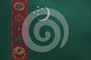 Turkmenistan flag depicted in paint colors on old brushed metal plate or wall closeup. Textured banner on rough background