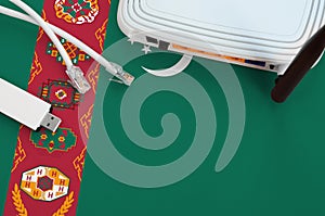 Turkmenistan flag depicted on table with internet rj45 cable, wireless usb wifi adapter and router. Internet connection concept