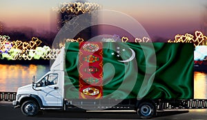 Turkmenistan flag on the side of a white van against the backdrop of a blurred city and river. Logistics concept