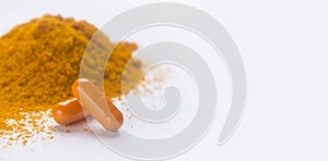 Turmeric or curcuma capsules, pile of orange powder on white