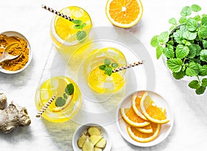 Turmeric, ginger, orange lemonade. Summer cold drink on light background, top view