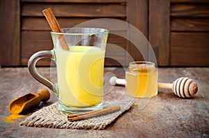 Turmeric golden milk latte with cinnamon sticks and honey. Detox liver fat burner, immune boosting, anti inflammatory drink photo