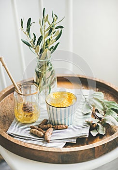 Turmeric latte, golden milk with honey on wooden tray