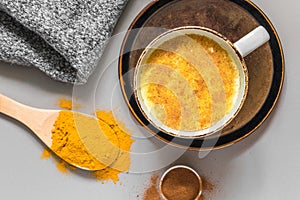 Turmeric latte with milk and cinnamon. Elixir of health and vivacity. Traditional healthy Indian detox drink. Grey background