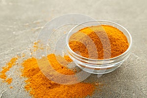 Turmeric powder in bowl on grey background