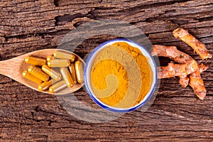 turmeric powder , capsule and roots curcumin on wooden plate