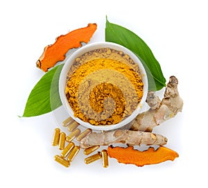 Turmeric powder and capsules in ceramic cup on wooden background