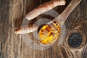 Turmeric powder and fresh root on a table, top view