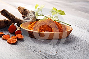 Turmeric powder and fresh turmeric on grey background