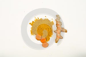 Turmeric powder and fresh turmeric roots isolated on a white background