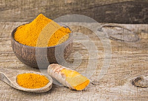 Turmeric powder and fresh turmeric on wooden background - Curcuma longa