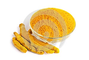 Turmeric powder in glass bowl with dry roots isolated on white background.