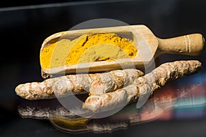 Turmeric powder Kurkuma in a wooden spoon and roots